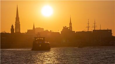 Eine Fähre fährt am Morgen bei Sonnenaufgang im Hamburger Hafen.