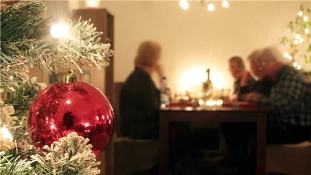 Eine Familie sitzt an Heiligabend gemeinsam am Tisch und genießt das Weihnachtsessen.