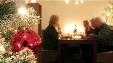 Eine Familie sitzt an Heiligabend gemeinsam am Tisch und genießt das Weihnachtsessen.