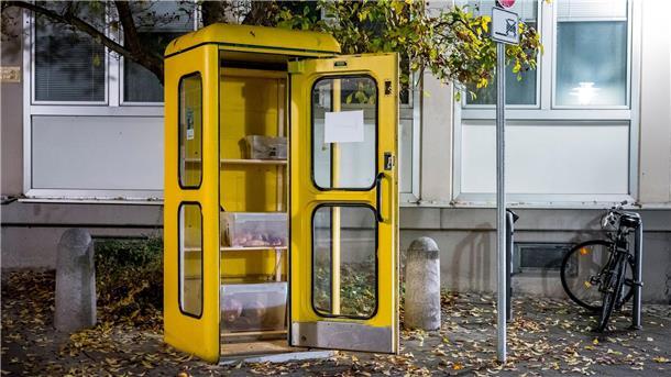 Eine „Foodsharing“-Station in einer gelben Telefonzelle ist mit Brötchen und Borten befüllt.