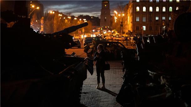 Eine Frau betrachtet zerstörte russische Panzer in Kiew.