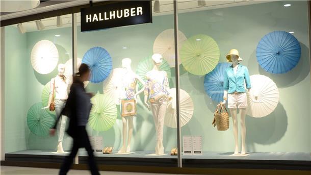 Eine Frau geht an einem Schaufenster des Modehauses Hallhuber in München vorbei.