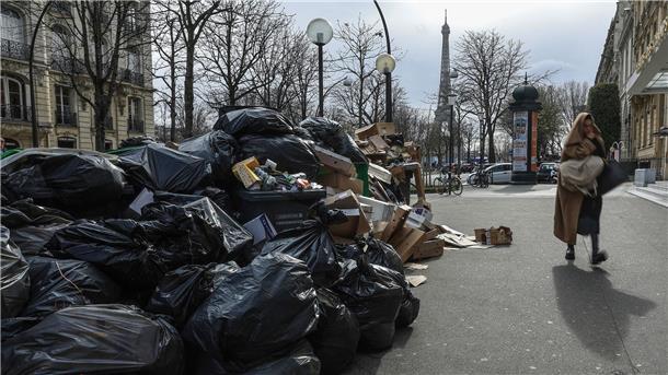 Eine Frau geht in Paris an nicht abgeholten Müllsäcken vorbei. Seit Wochen wird das öffentliche Leben in Frankreich durch die Proteste gegen die Rentenreform eingeschränkt - auch durch Streiks bei der Müllabfuhr.