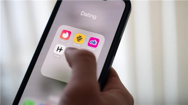 Eine Frau hält ein Smartphone, auf dem Dating-Apps angezeigt werden. (Symbolbild)