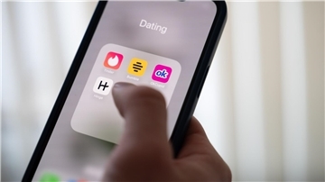 Eine Frau hält ein Smartphone, auf dem Dating-Apps angezeigt werden. (Symbolbild)