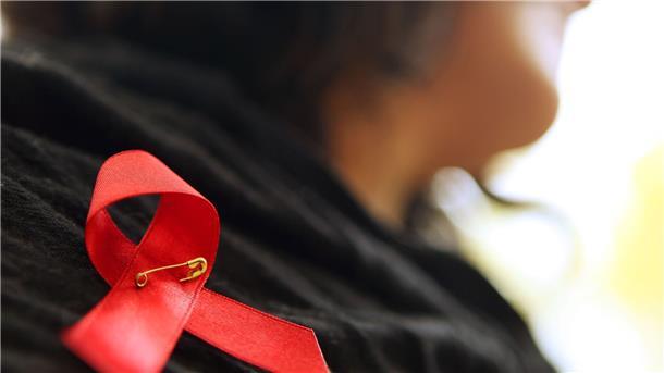 Geschätzte Zahl der HIV-Neuinfektionen stagniert Eine Frau hat sich eine rote Schleife angeheftet.