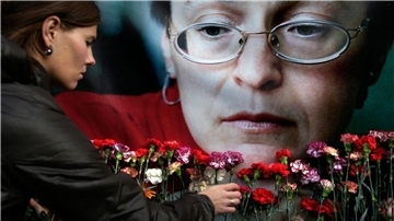 Eine Frau legt in Moskau Blumen vor einem Porträt der ermordeten russischen Journalistin Anna Politkowskaja nieder.