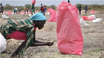 Eine Frau sammelt im südsudanesischen Kandak Hirse vom Boden auf, die in Säcken vom Welternährungsprogramm der Vereinten Nationen über der Stadt abgeworfen wurden.