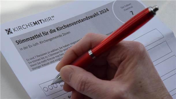Eine Frau setzt ein Kreuz auf einen Stimmzettel für die Wahl des Kirchenvorstands in Zeven.