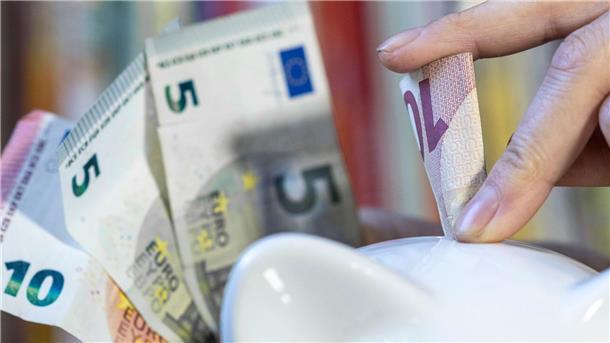Eine Frau steckt einen 10 Euroschein in ein Sparschwein.