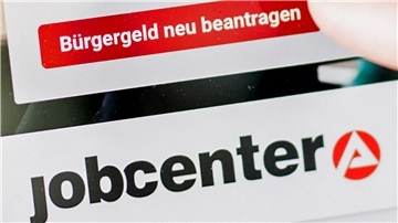 Eine Frau tippt auf einem Tablet auf einen Link zum Beantragen des Bürgergeldes.
