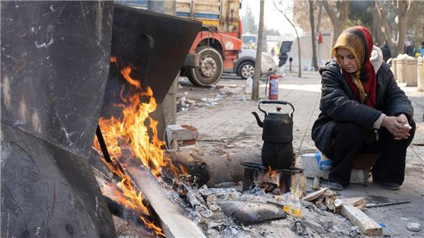 Eine Frau wärmt sich im türkischen Kahramanmaras an einem Feuer.