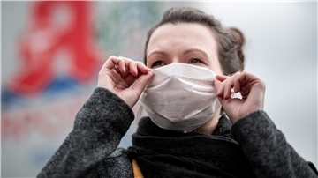 Eine Frau zieht sich eine Gesichtsmaske an - auch in Bremerhaven und Bremen wappnet man sich gegen das Coronavirus.