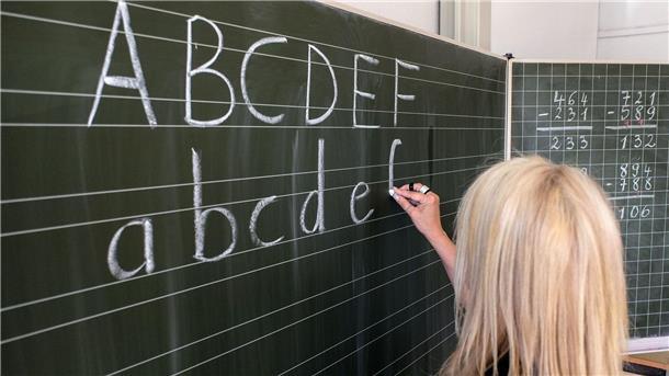 Mehr Plätze für Schulkinder mit Förderbedarf in Bremen Eine Grundschullehrerin schreibt die ersten Buchstaben des Alphabets auf eine Schultafel in einem Klassenzimmer.