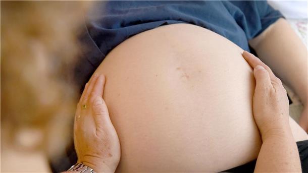 Hebammen-Mangel: Geburtshelferinnen fordern Anerkennung Eine Hebamme tastet den Bauch einer Frau ab, die im neunten Monat schwanger ist.