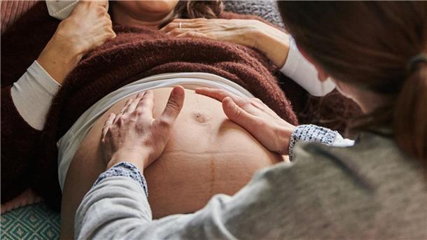 Eine Hebamme tastet in ihrer Berliner Praxis den Bauch einer schwangeren Frau ab.