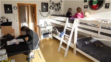 Eine Jugendliche und zwei Kinder beschäftigen sich in ihrem Zimmer in einem Kinderheim. 
