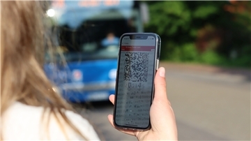 Eine junge Frau blickt auf ein 9-Euro-Ticket auf einem Smartphone. Seit dem 1. Juni gilt das Rabattticket in Bus und Bahn.