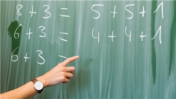 Eine junge Lehrerin schreibt an einer Schultafel im Mathematikunterricht. Wird die Rechnung mit dem Modell Praxislehrer aufgehen? 