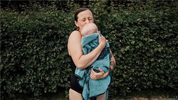 Eine junge Mutter drückt im Freibad ihr Kind an sich. Dieser Moment, den die Fotografin Sophie Kirchner festgehalten hat, drückt innige Verbundenheit aus.
