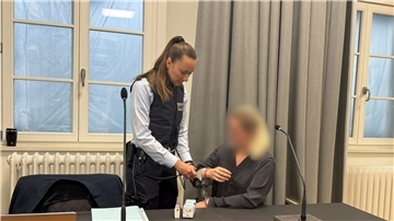Eine Justizmitarbeiterin nimmt der Angeklagten beim Prozessauftakt vor dem Landgericht Ravensburg die Handschellen ab.