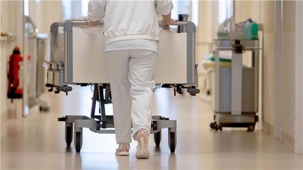 Einigung zur Finanzierung der Kliniken erzielt Eine Krankenpflegerin schiebt ein Krankenbett durch einen Flur.