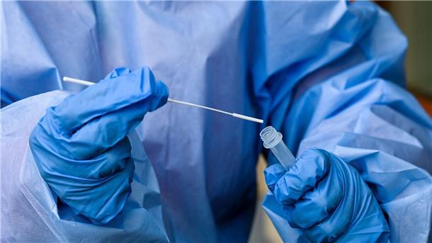 Eine Krankenschwester steckt ein Abstrichstäbchen in die Flüssigkeit eines Corona-Schnelltests.