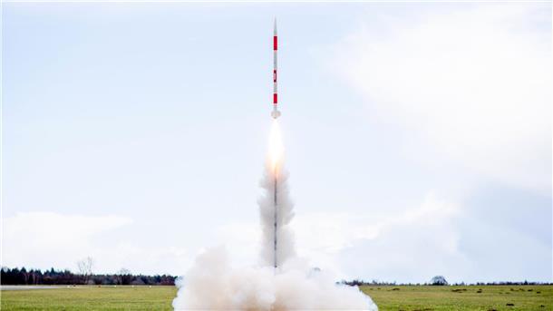 Schülerteam gewinnt deutschen Minisatelliten-Wettbewerb Eine mit mehreren Minisatelliten bestückte Rakete startet 2023 von einer Wiese auf dem Flugplatz.