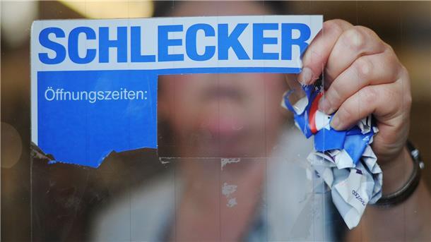 Schlecker-Insolvenz: Millionen-Klage wird neu geprüft Eine Mitarbeiterin der Drogeriemarktkette Schlecker reißt das Firmenlogo von der Eingangstür einer Filiale.