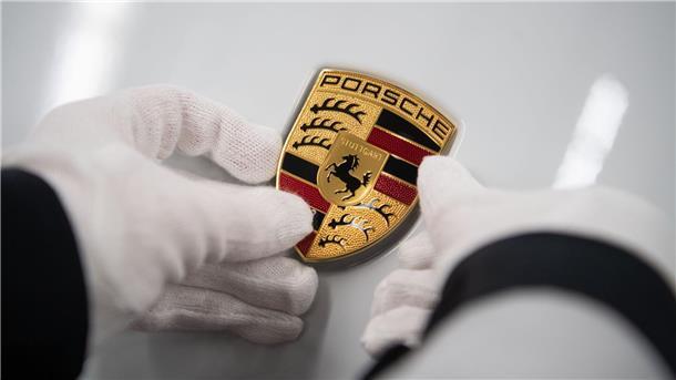 VW-Sportwagentochter Porsche hält trotz China-Problemen Spur Eine Mitarbeiterin der Porsche AG hält in der Produktion ein Porsche-Emblem auf die Motorhaube eines Porsche Taycan.