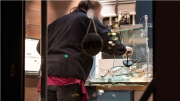 Eine Mitarbeiterin der Spurensicherung untersucht nach dem Überfall in Hamburg  eine eingeschlagene Vitrine.