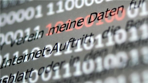 Mehr Beschwerden über Datenschutzverletzungen Eine Musterdatenschutzerklärung wird vor einen Bildschirm mit roten Einsen und Nullen gehalten.