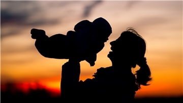 Eine Mutter hebt vor dem Abendhimmel ihr Baby in die Luft. Weil viele Menschen aus Nordenham weggezogen sind, ist die Region in den vergangenen Jahr bei der Einwohnerzahl geschrumpft. Dieser Trend konnte gestoppt werden.