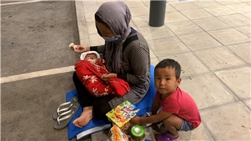 Eine Mutter sitzt mit ihren KIndern beim Essen am Straßenrand. Die Zustände in den Lagern auf Lesbos sind für einige Flüchtlinge unerträglich.