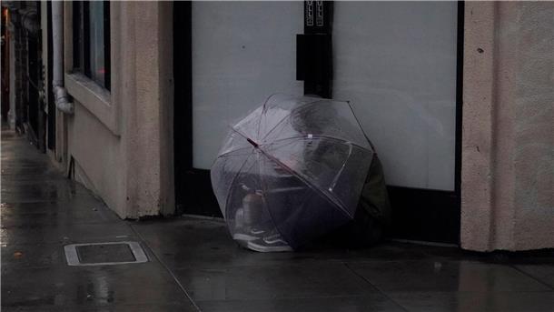 Eine Person versucht in San Francisco, sich  unter einem Schirm vor Regen zu schützen.