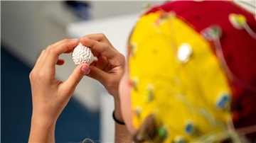 Eine Probandin trägt eine EEG-Haube mit Elektroden für die Messung.