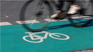 Eine Radfahrerin fährt in Leipzig über einen grün eingefärbten Radweg.