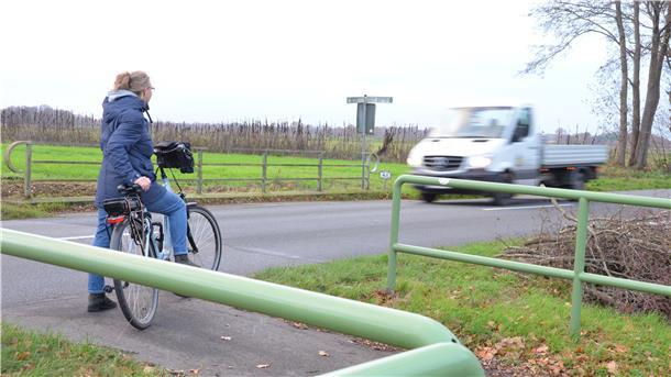 Eine Radfahrerin steht an der Straße zwischen Dipshorn im Landkreis Rotenburg und Otterstedt im Landkreis Verden. An der Kreisgrenze endet der Radweg. Daran wird sich so schnell auch nichts ändern.