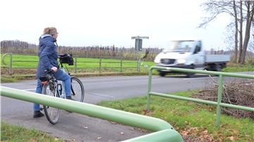 Eine Radfahrerin steht an der Straße zwischen Dipshorn im Landkreis Rotenburg und Otterstedt im Landkreis Verden. An der Kreisgrenze endet der Radweg. Daran wird sich so schnell auch nichts ändern.
