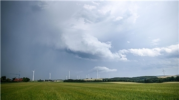 Eine Regenfront mit dunklen Wolken hinter einem Gerstenfeld. (Symbolbild)