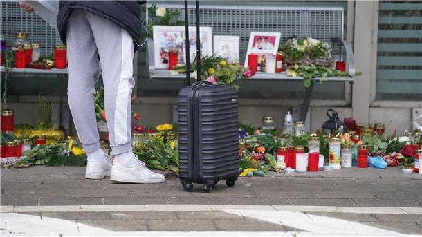 Tödliche Messerattacke im Zug: Minister beraten Konsequenzen Eine Reisende schaut sich die Blumen, Kerzen und verschiedene Bilder im Wartehäuschen am Bahnhof zum Gedenken an die Opfer der Messerattacke an.