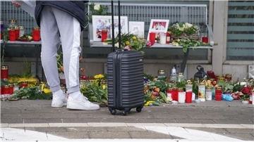 Eine Reisende schaut sich die Blumen, Kerzen und verschiedene Bilder im Wartehäuschen am Bahnhof zum Gedenken an die Opfer der Messerattacke an.