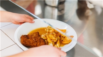 Eine Schülerin nimmt einen Teller vom Tresen der Essensausgabe einer Schulmensa. An fünf Tagen in der Woche bekommen die Schüler in der KGS Tarmstedt ein warmes Essen in der Mittagspause.