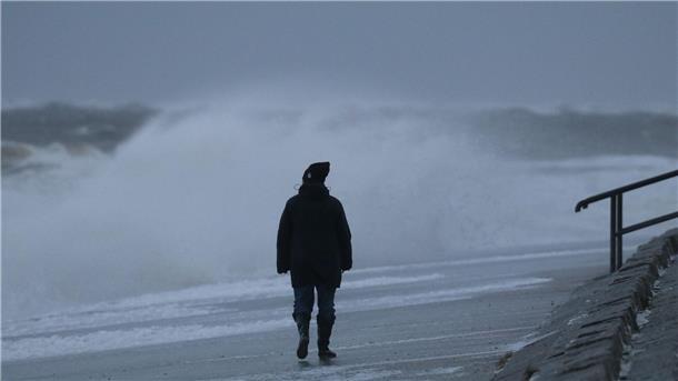 Sturmfluten verursachen leichte Sandverluste auf Inseln Eine Spaziergängerin läuft bei stürmischem Wetter am Nordstrand der ostfriesischen Insel Norderney.