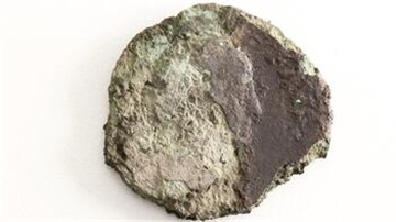 Eine stark korrodierte Münze haben Archäologen in Schiffdort ausgegraben. Rechts der Mitte sind Nase und Gesicht eines noch nicht identifizierten römischen Kaisers im Profil zu erkennen.