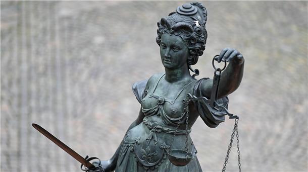 Eine Statue der Justitia hält eine Waage und ein Schwert in der Hand.