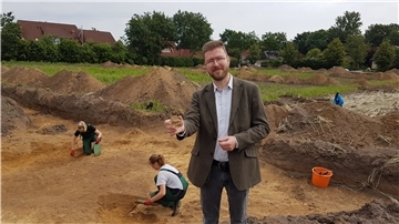 Eine Tonscherbe könnte einen Hinweis darauf geben, wann hier Menschen gesiedelt haben. Kreisarchäologe Dr. Stefan Hesse präsentiert das frisch freigelegte Fundstück an der Grabungsstätte am Rande Bülstedts.