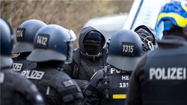 Protest gegen Waldrodung für Autobahn-Ausbau Eine vermummte Person steht im Fechenheimer Wald der Polizei gegenüber.