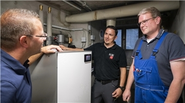 Experten stehen neben einer Wärmepumpe im Keller eines Hauses