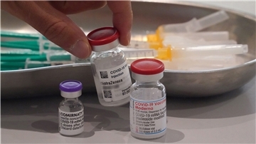 Ein Mitarbeiter des Impfzentrums in den Messehallen nimmt eine Impfdose vom Impfstoff Astrazeneca vom Tisch. Links im Bild steht eine Impfdose vom Impfstoff Biontech, rechts im Bild steht eine Impfdose vom Impfstoff Moderna. 